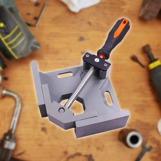 Clamp on a wooden surface with tools in the background